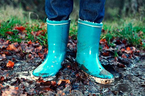 a child's turquoise welly boots in the mud